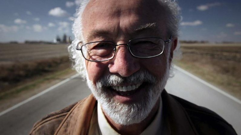A laughing white-bearded man on a straight country road