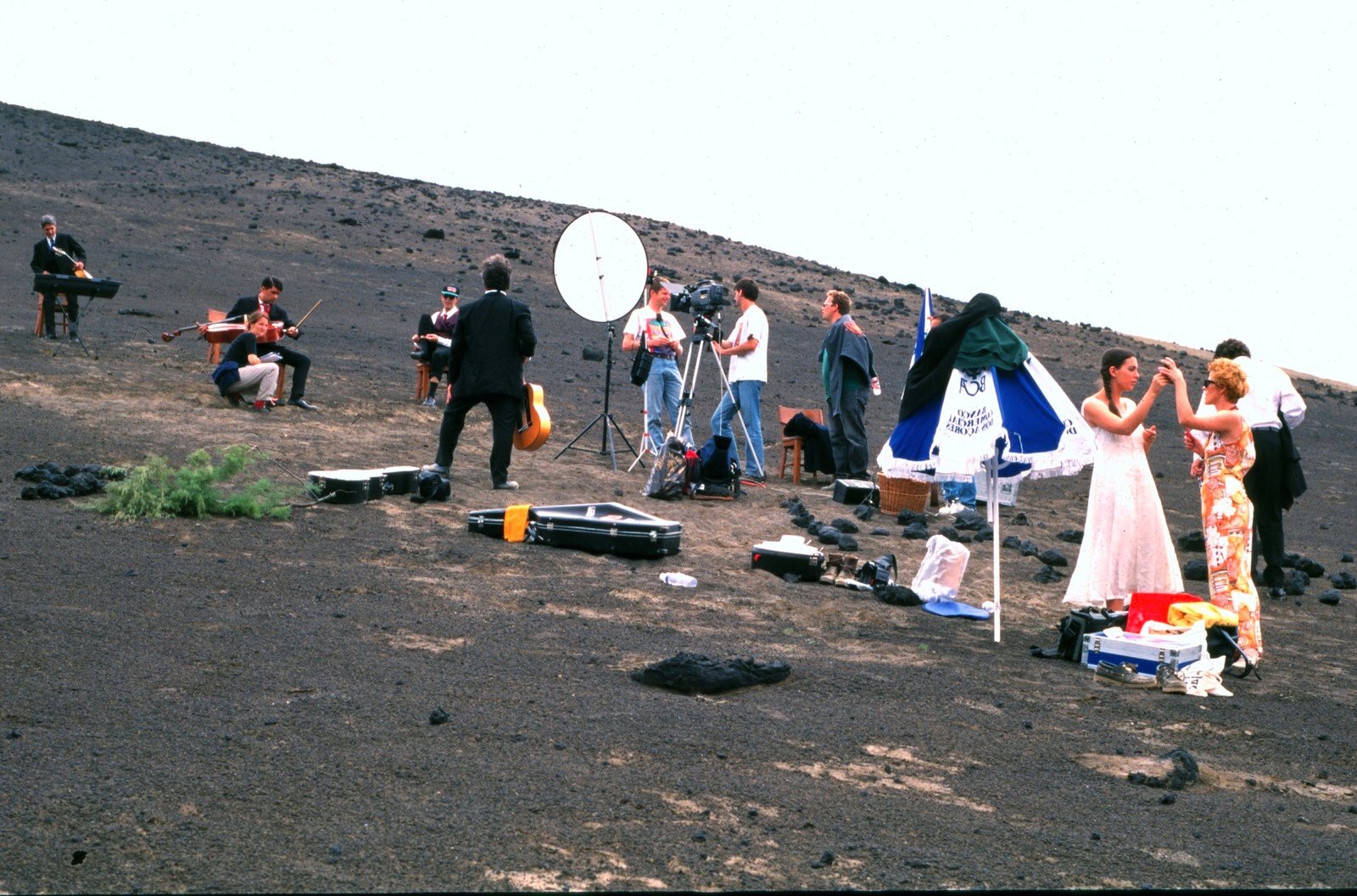 A wide slope of dark ash with musicians, a reflector, a parasol and equipment cases spread out