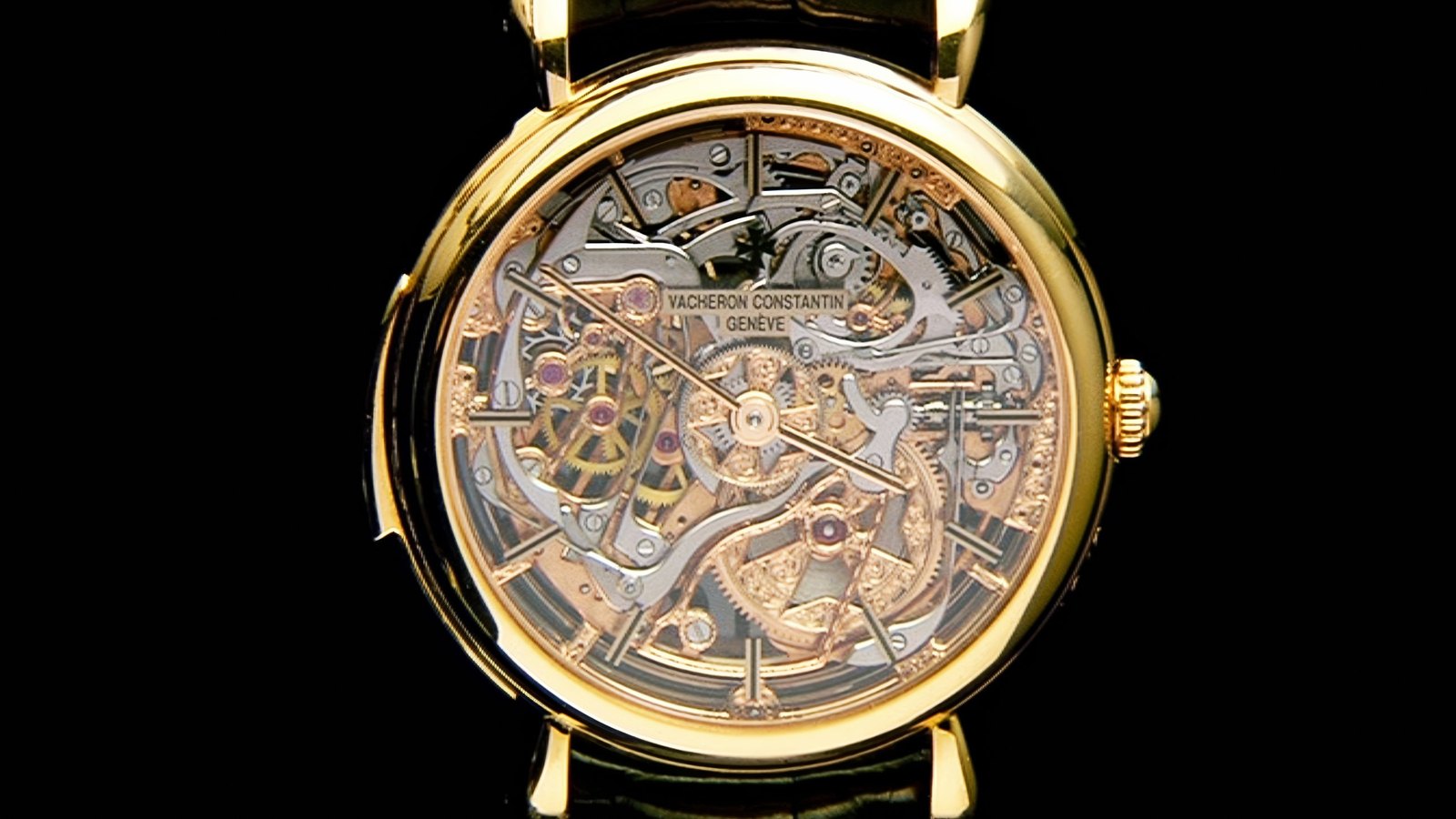 The back of a Vacheron Constantin watch in yellow gold, the skeleton movement visible through the open dial, on a black background.