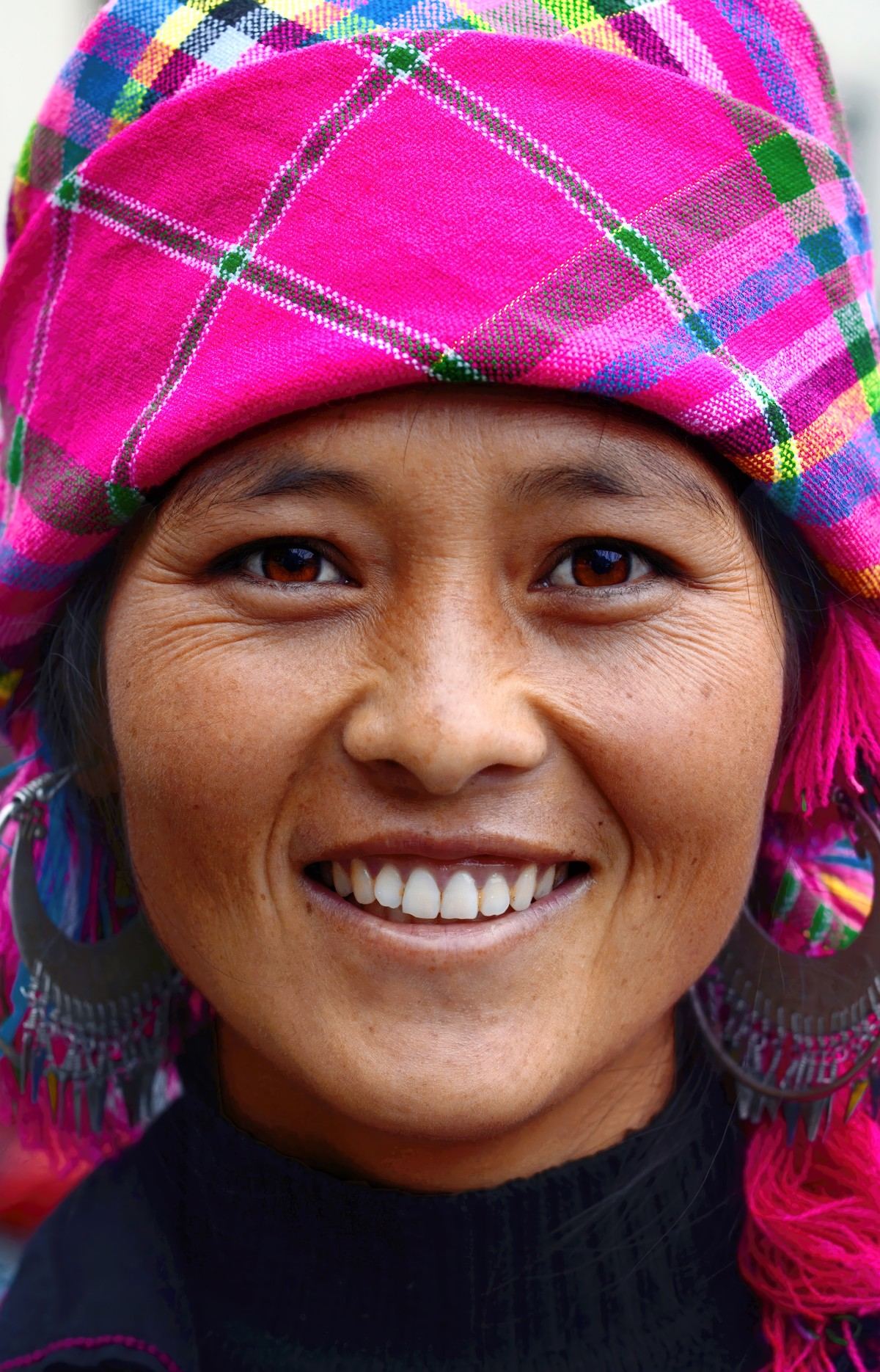 A smiling woman in a pink checked headscarf