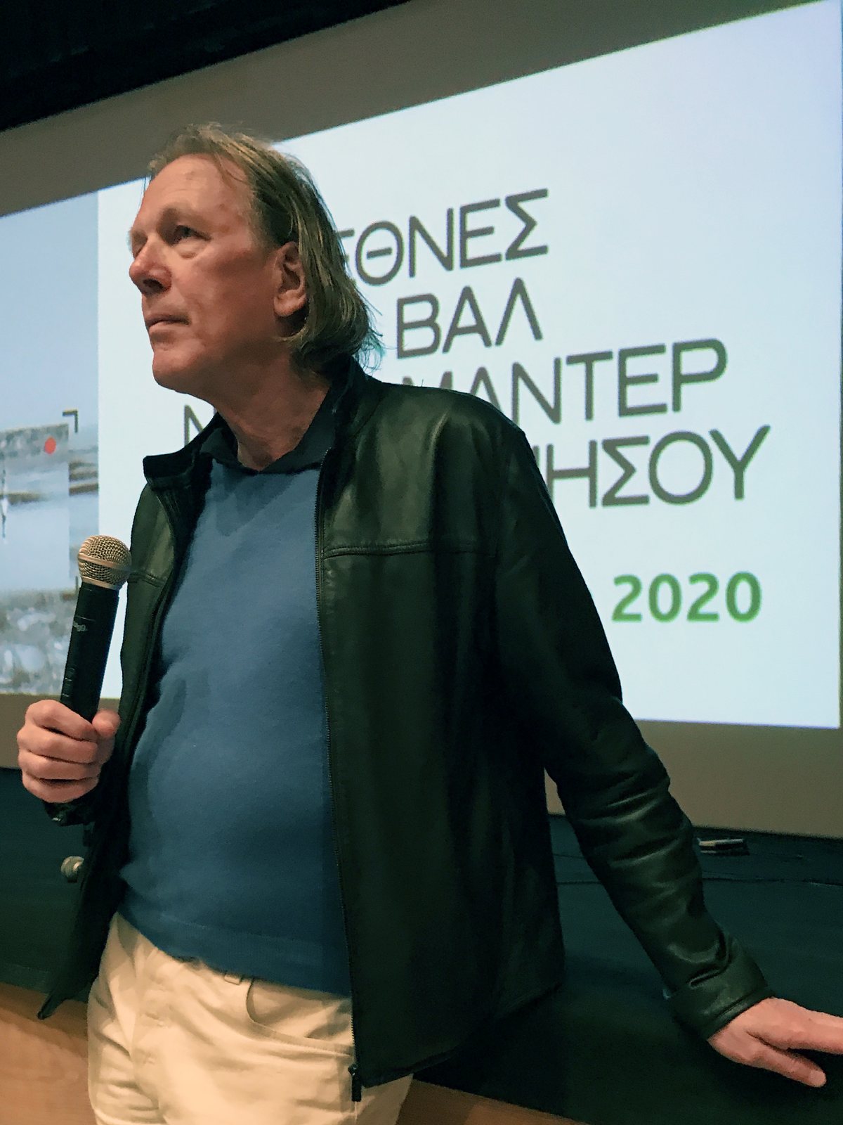Rob Rombout speaking into a microphone in front of a festival screen
