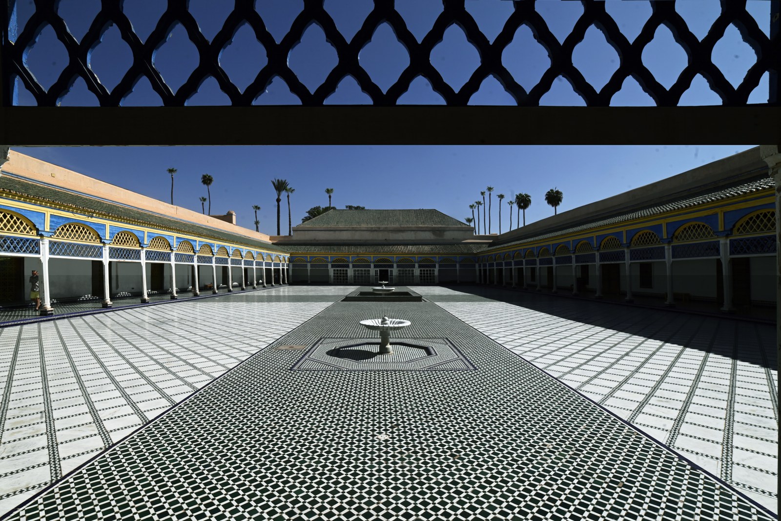 A tiled courtyard seen from under a carved lattice