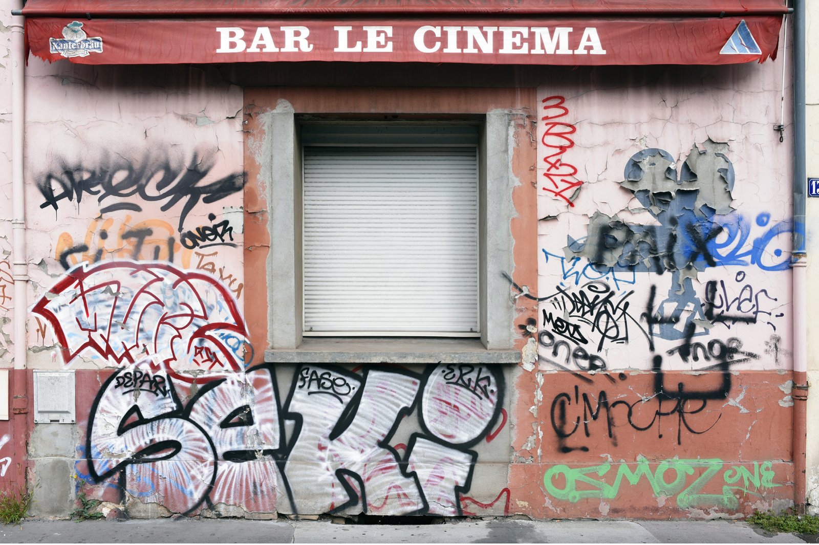 A closed bar front covered in graffiti, the sign reading Bar le Cinéma